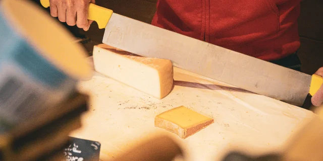A lady dressed in red cutting cheese.