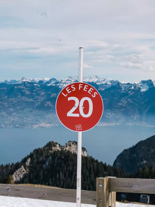 Haut Des Pistes De Ski Thollon Les Memises. Op de voorgrond staat een bord dat de rode piste Les Fées aangeeft. Op de achtergrond zijn het meer van Genève en de Zwitserse bergen te zien.