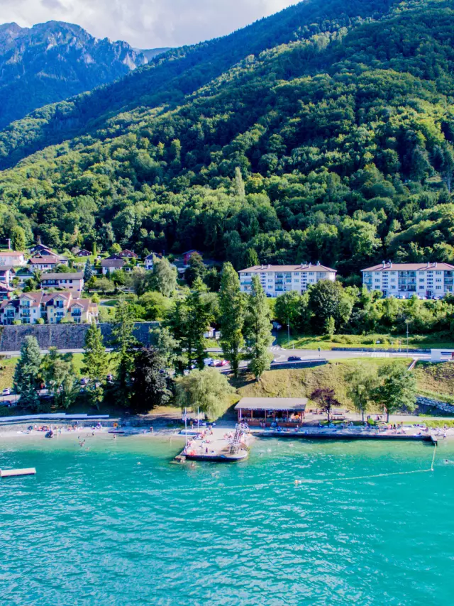 Drone view from the lake. The water is blue and you can see the mountain in the background with the port.