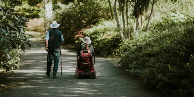 Personne marchant avec une canne et une autre en fauteuil roulant