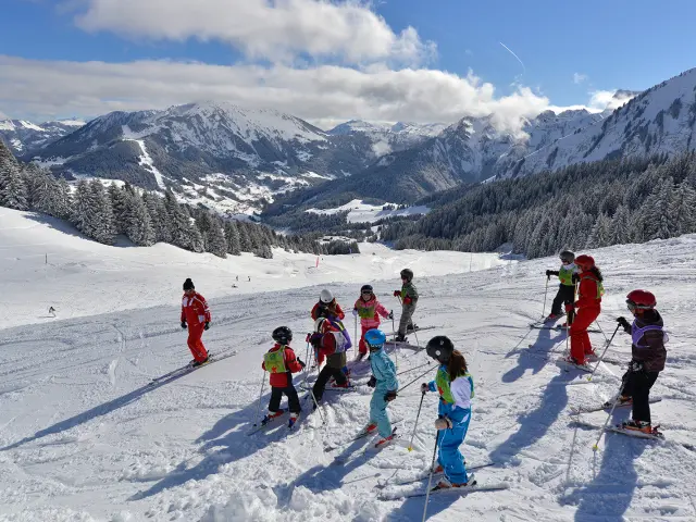 Des enfants du club piou piou d'Abondance, avec les moniteurs de ski de l'ESF, en plein apprentissage ski sur fond de montagnes enneigées